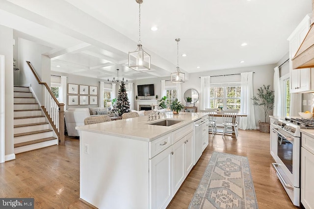 kitchen featuring hanging light fixtures, white cabinetry, a kitchen island with sink, and gas range gas stove