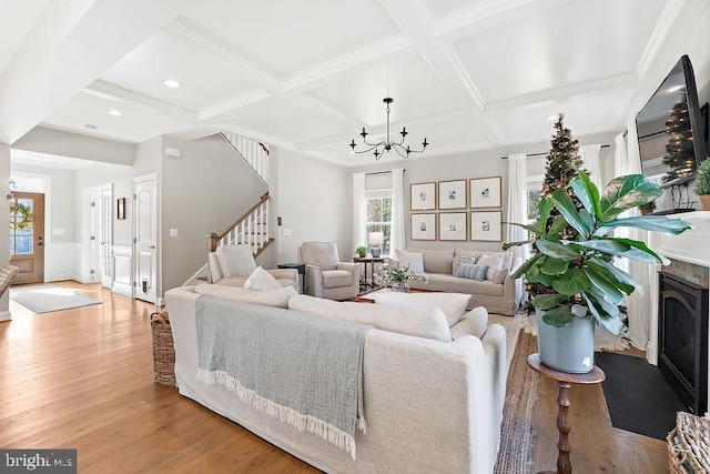 living room with a chandelier, beam ceiling, light wood-type flooring, and coffered ceiling