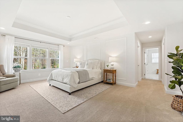 carpeted bedroom featuring ornamental molding, connected bathroom, and a tray ceiling