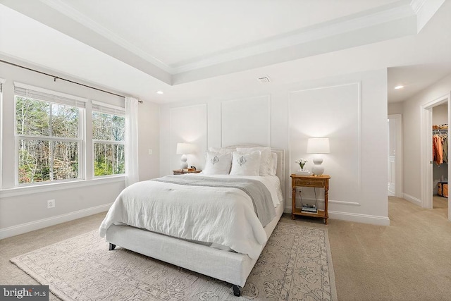 carpeted bedroom featuring a tray ceiling, a spacious closet, a closet, and ornamental molding