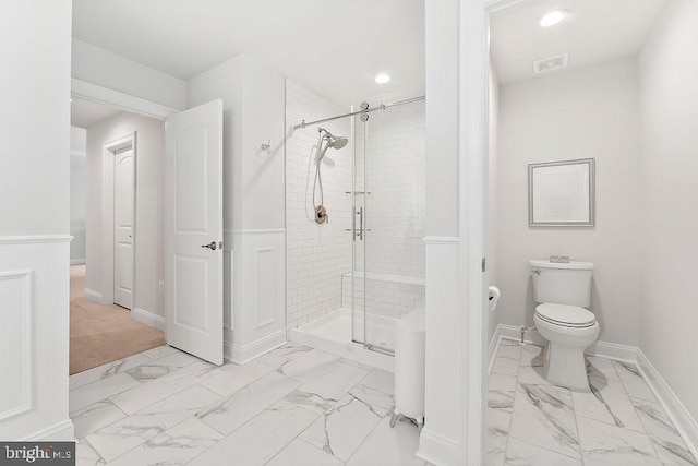 bathroom featuring toilet and a shower with door