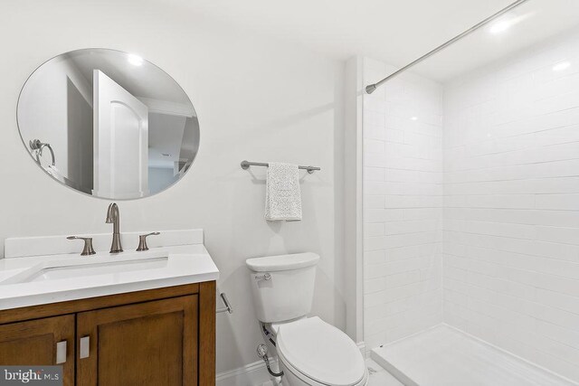 bathroom with tiled shower, vanity, and toilet