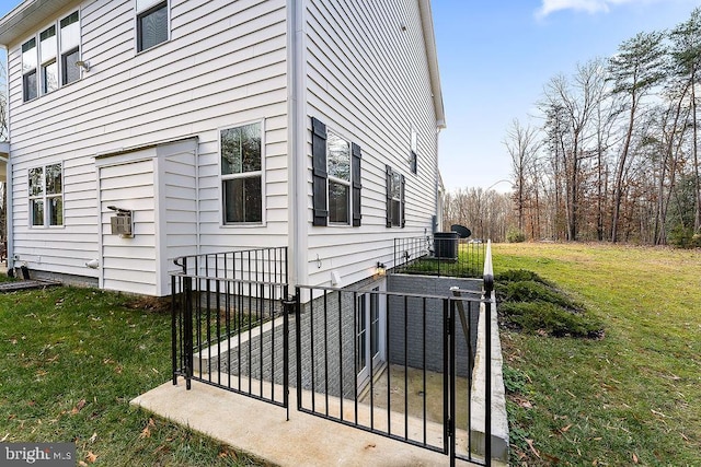 view of side of home with central AC unit and a yard