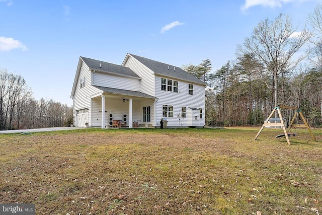 back of house with a playground, ceiling fan, a yard, and a garage