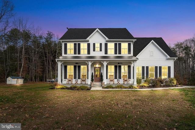 colonial house with a yard, a porch, and a storage shed