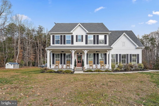 colonial inspired home featuring a porch, a front lawn, and a storage shed