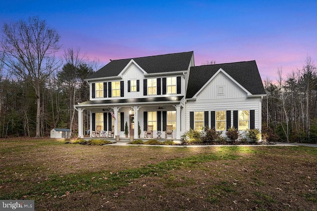 colonial inspired home with a lawn, a porch, and a shed