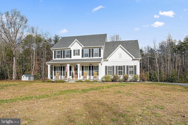 view of front of home featuring a front yard, a porch, and a storage shed