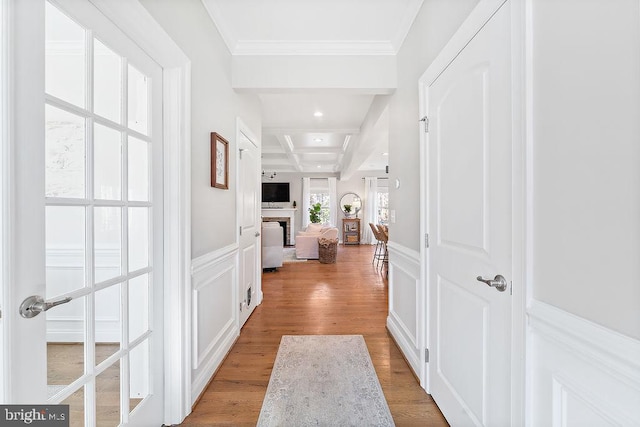 corridor with beamed ceiling, light wood-type flooring, crown molding, and coffered ceiling