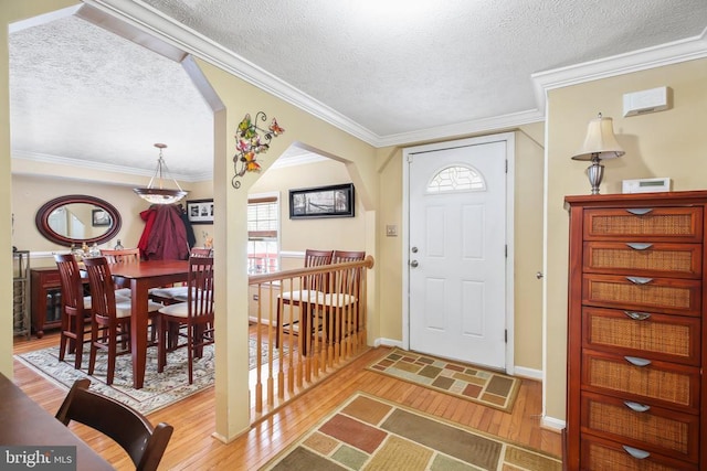 entrance foyer with hardwood / wood-style floors, a textured ceiling, and crown molding