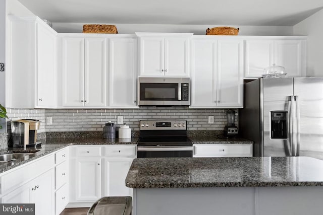 kitchen with backsplash, white cabinetry, dark stone counters, and appliances with stainless steel finishes