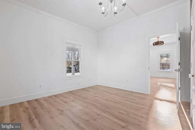 spare room featuring plenty of natural light, light hardwood / wood-style floors, crown molding, and an inviting chandelier