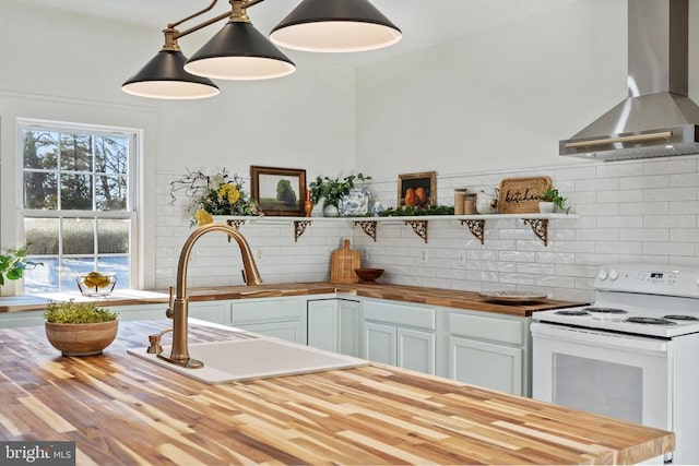 kitchen with butcher block counters, sink, wall chimney exhaust hood, white electric range, and decorative light fixtures