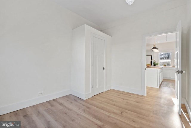 spare room featuring sink and light wood-type flooring