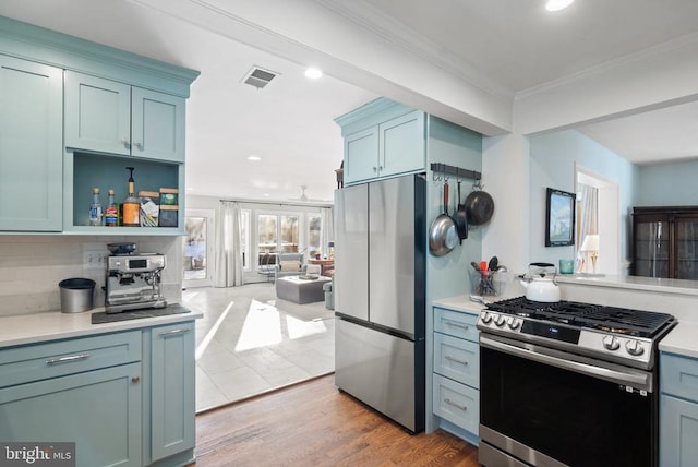 kitchen with stainless steel appliances, crown molding, decorative backsplash, and hardwood / wood-style flooring