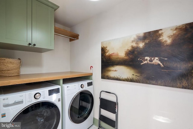 laundry area featuring heating unit, washing machine and clothes dryer, and cabinets