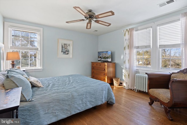 bedroom featuring ceiling fan, wood-type flooring, and radiator heating unit