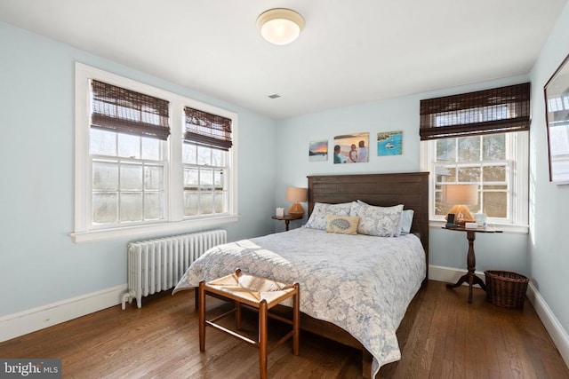 bedroom with hardwood / wood-style flooring, multiple windows, and radiator