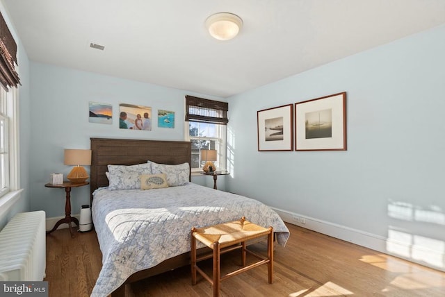 bedroom with radiator heating unit and hardwood / wood-style floors