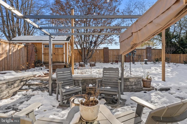 snow covered patio featuring a storage shed