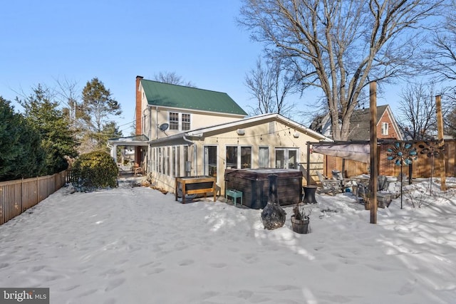 snow covered back of property with a hot tub