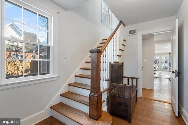 staircase with wood-type flooring, a wealth of natural light, and french doors