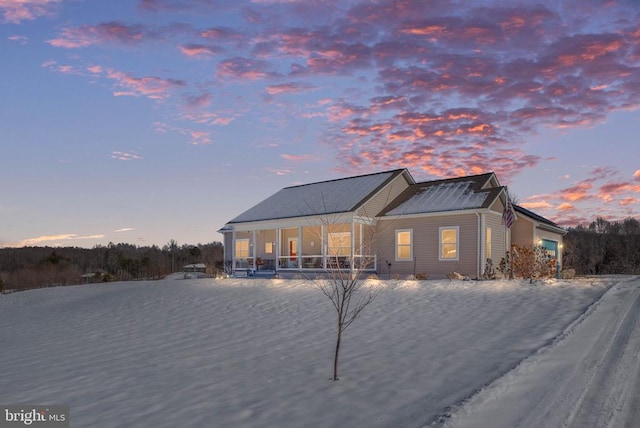 back house at dusk featuring covered porch