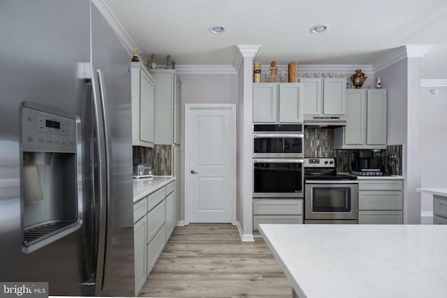 kitchen featuring decorative backsplash, light wood-type flooring, crown molding, and appliances with stainless steel finishes