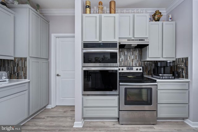 kitchen featuring decorative backsplash, light wood-type flooring, crown molding, and appliances with stainless steel finishes