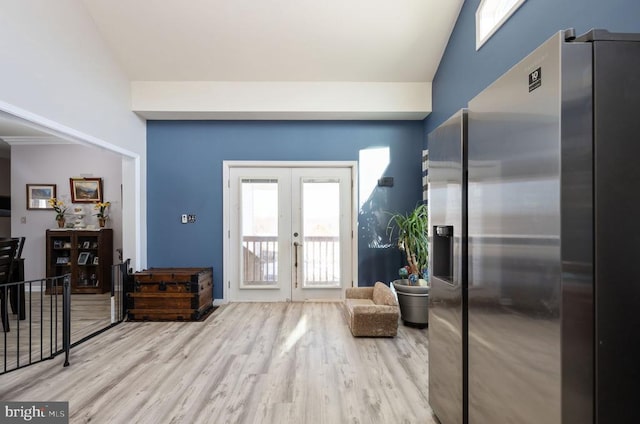 entrance foyer featuring vaulted ceiling, light wood-type flooring, and french doors