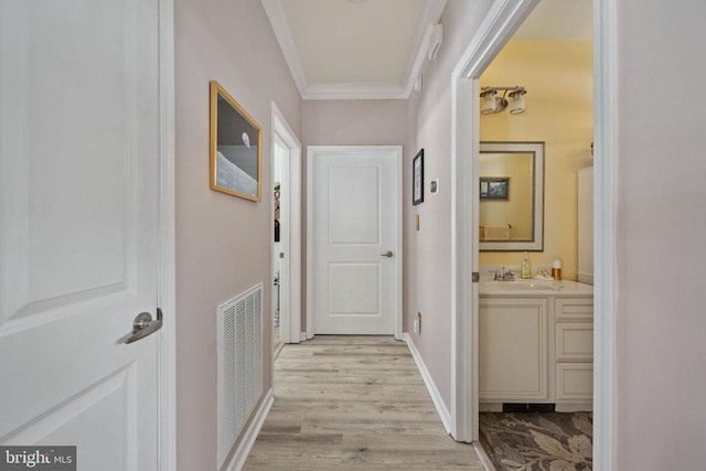 corridor featuring sink, ornamental molding, and light hardwood / wood-style flooring