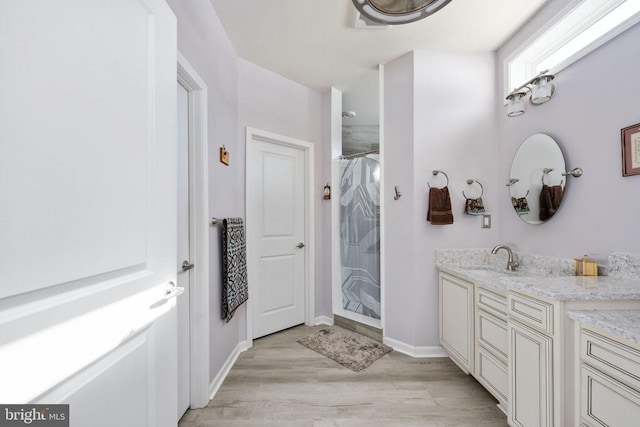 bathroom with walk in shower, vanity, and wood-type flooring