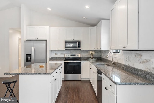 kitchen with decorative backsplash, appliances with stainless steel finishes, dark stone countertops, a center island, and white cabinetry