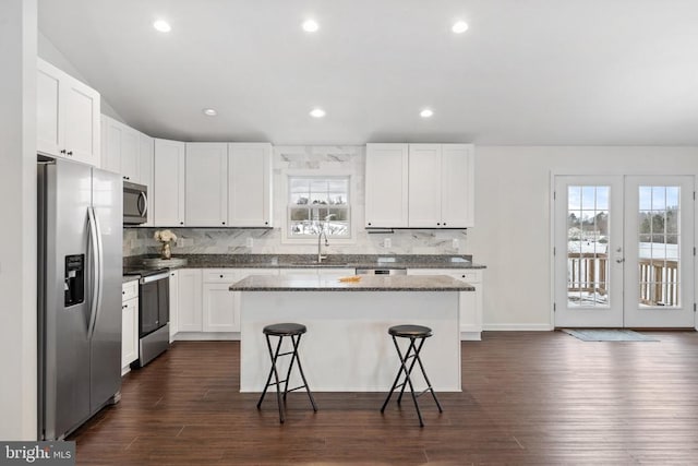 kitchen featuring white cabinetry, french doors, a kitchen bar, a kitchen island, and appliances with stainless steel finishes