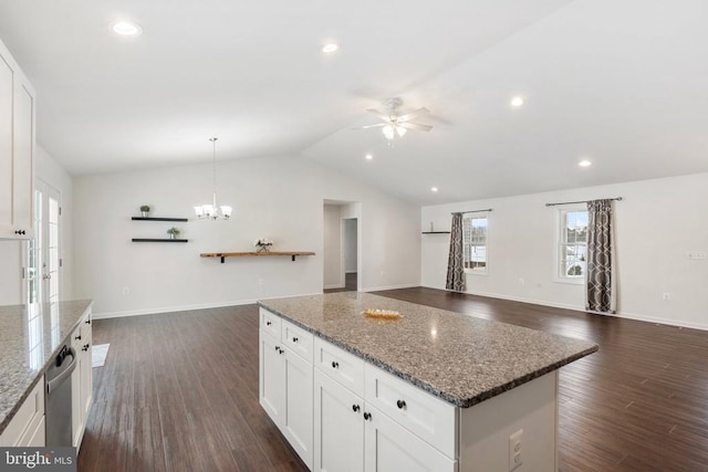 kitchen with lofted ceiling, ceiling fan with notable chandelier, dark stone countertops, decorative light fixtures, and white cabinetry