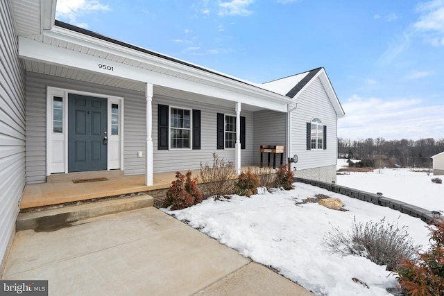 snow covered property entrance with covered porch