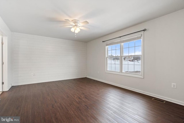 empty room with dark hardwood / wood-style floors and ceiling fan