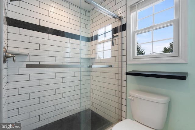 bathroom featuring a tile shower and toilet