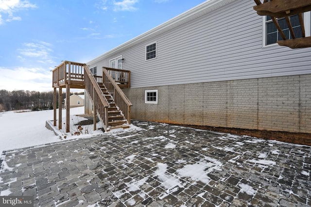 snow covered patio with a wooden deck