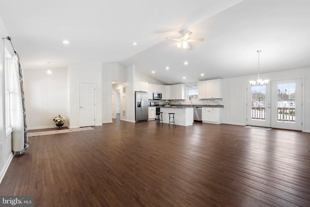 unfurnished living room with ceiling fan with notable chandelier, sink, dark wood-type flooring, and vaulted ceiling