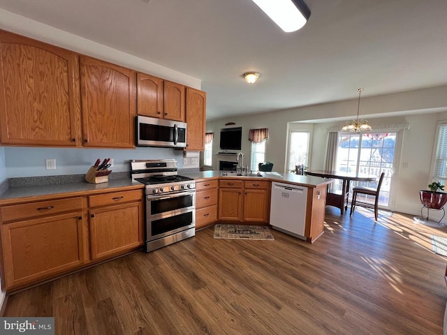 kitchen featuring sink, an inviting chandelier, kitchen peninsula, decorative light fixtures, and appliances with stainless steel finishes