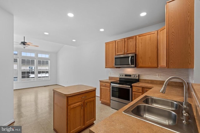 kitchen with appliances with stainless steel finishes, a center island, sink, backsplash, and ceiling fan