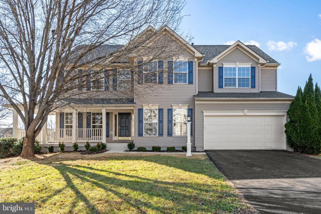 view of front facade featuring a porch, a front lawn, and a garage