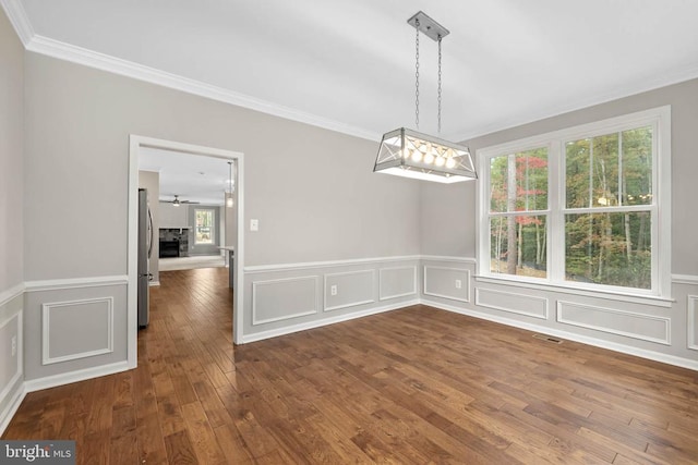 unfurnished dining area featuring ceiling fan, crown molding, and dark hardwood / wood-style floors