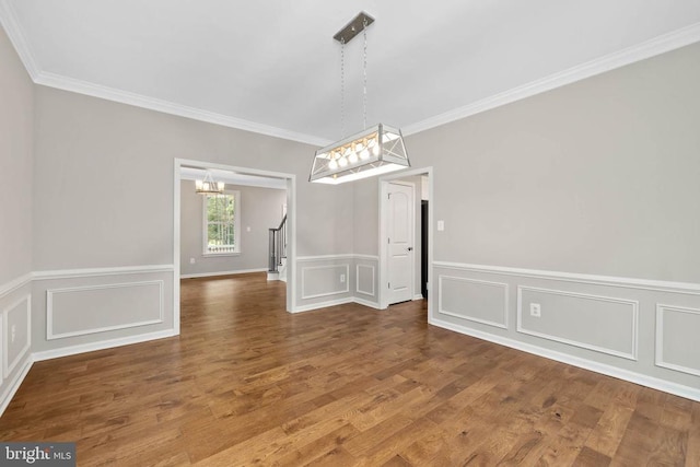 unfurnished dining area with a notable chandelier, hardwood / wood-style flooring, and crown molding