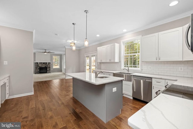 kitchen featuring stainless steel dishwasher, a center island with sink, white cabinetry, and ceiling fan