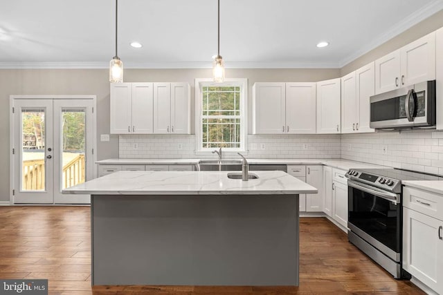 kitchen featuring an island with sink, appliances with stainless steel finishes, light stone countertops, and white cabinetry