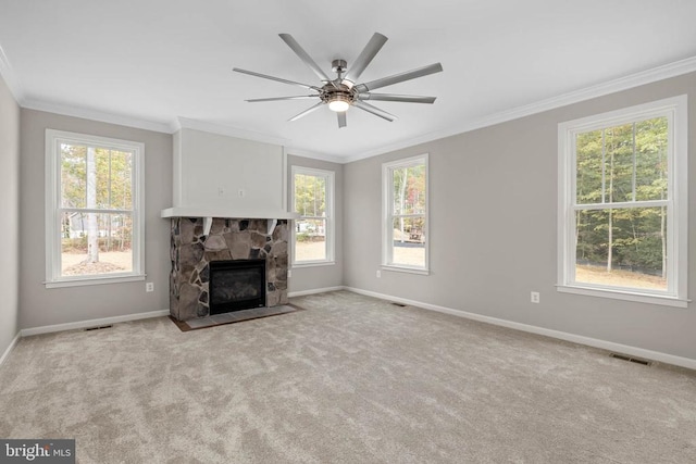 unfurnished living room featuring a fireplace, light carpet, ceiling fan, and crown molding