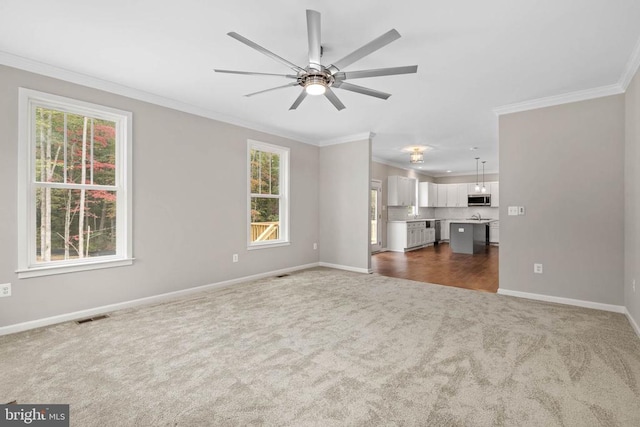 unfurnished living room with ceiling fan, crown molding, and dark carpet