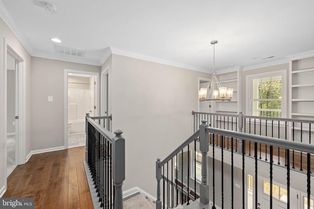 hall with dark wood-type flooring, a notable chandelier, and ornamental molding